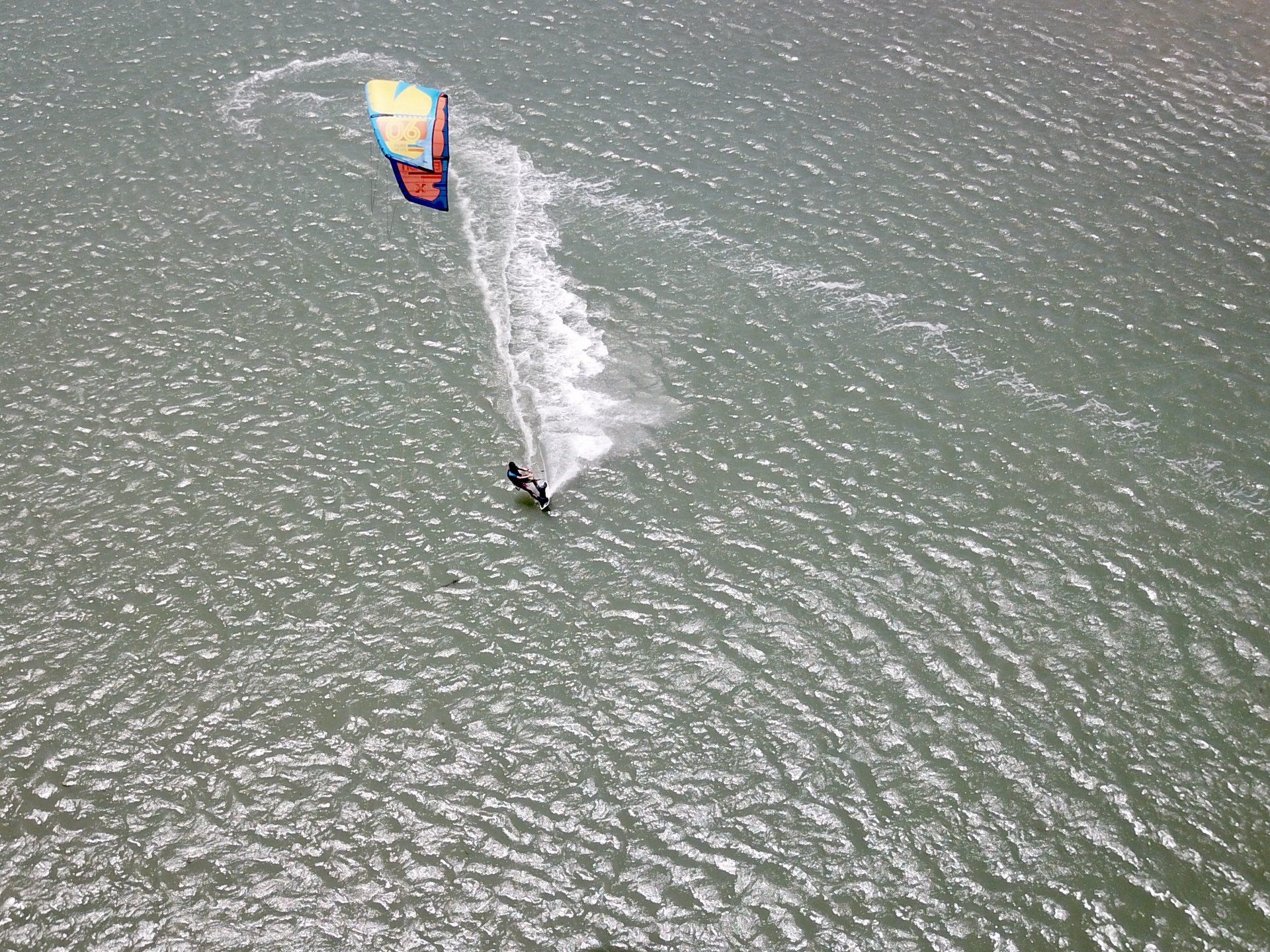 Uma pessoa está empinando uma pipa sobre um corpo d'água