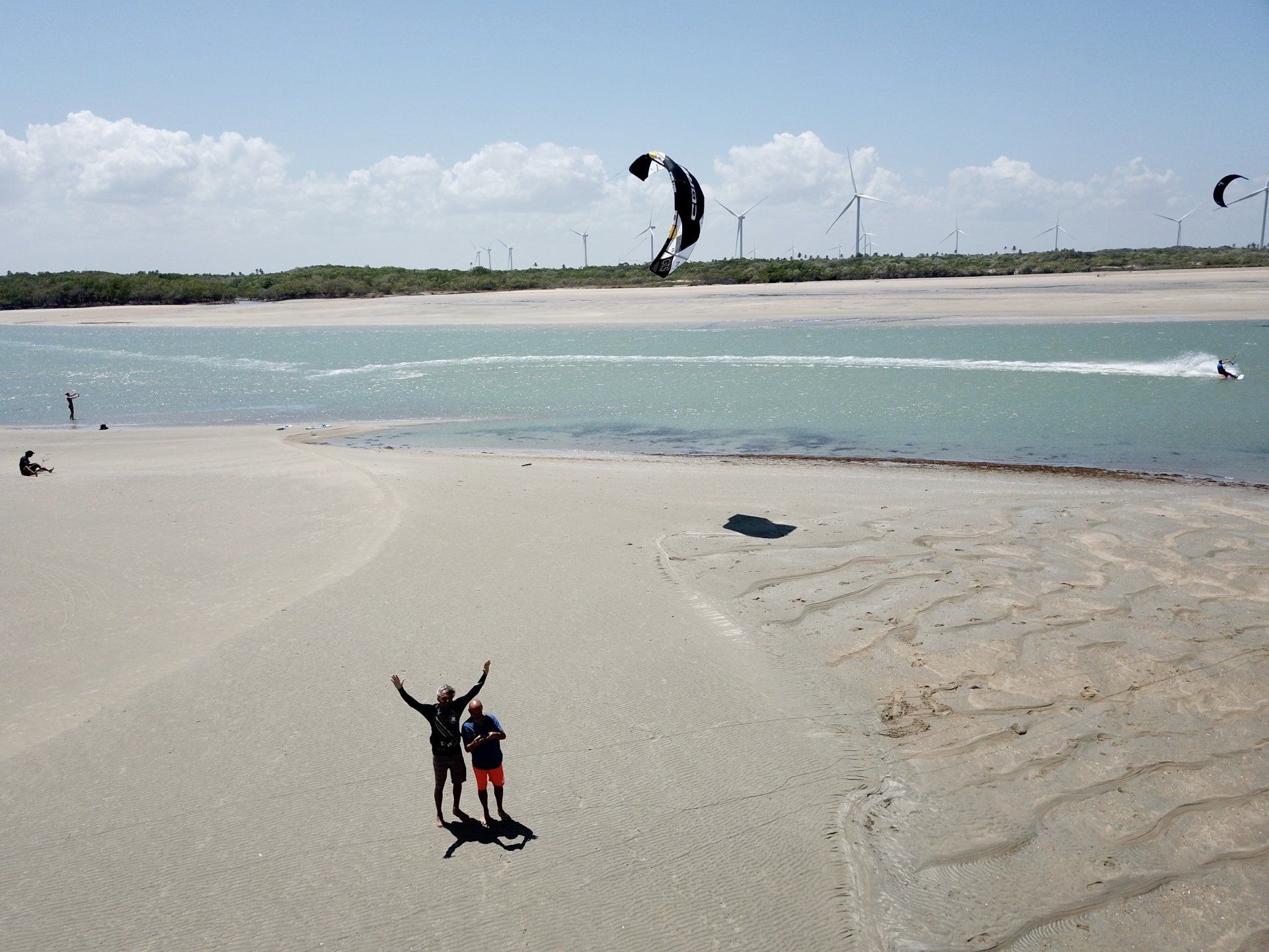 Um casal em pé em uma praia de areia com os braços estendidos