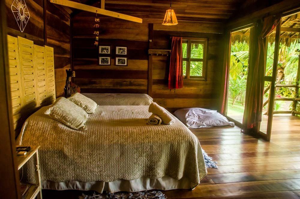Há uma cama no meio do quarto em uma cabana de madeira.