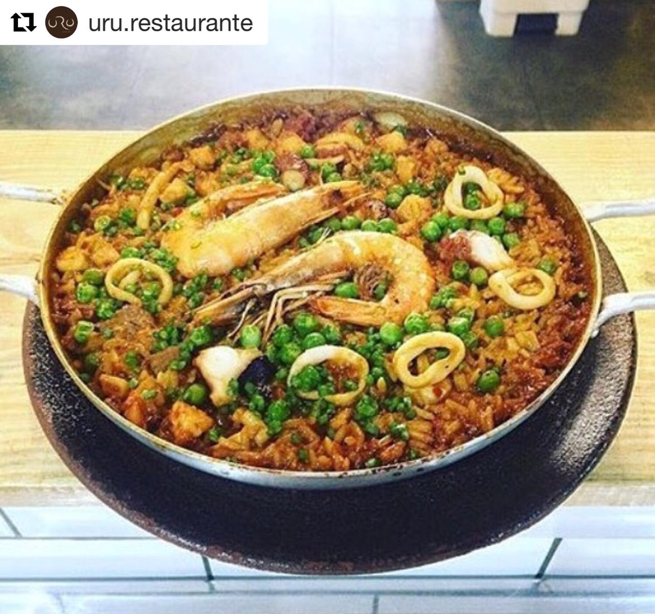 Uma panela de paella com camarão e ervilhas sobre uma mesa
