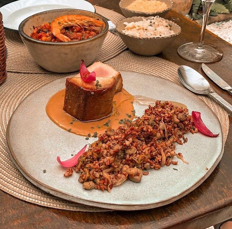 Um prato de comida sobre uma mesa com tigelas de comida ao fundo