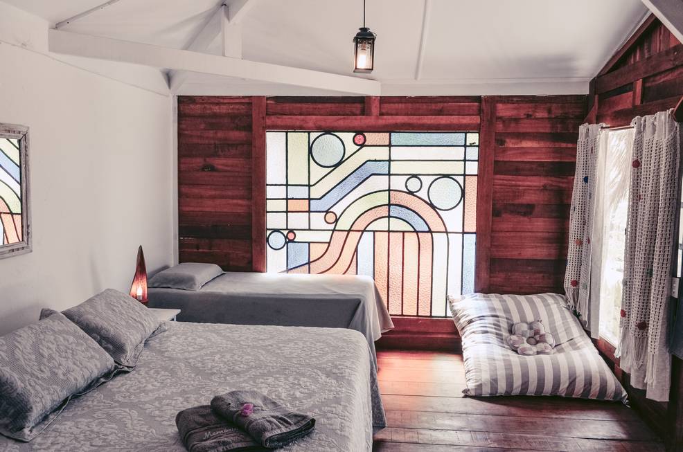 Um quarto com três camas e um vitral.