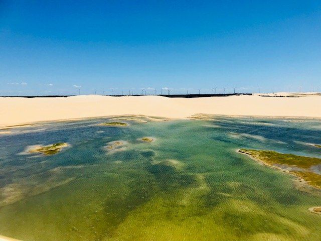 Há um grande corpo de água no meio de uma praia arenosa.