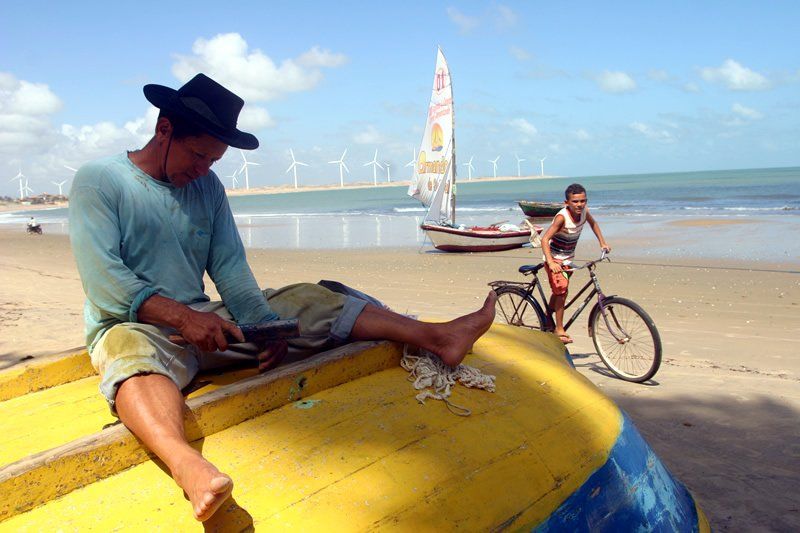 Um homem está sentado na lateral de um barco na praia