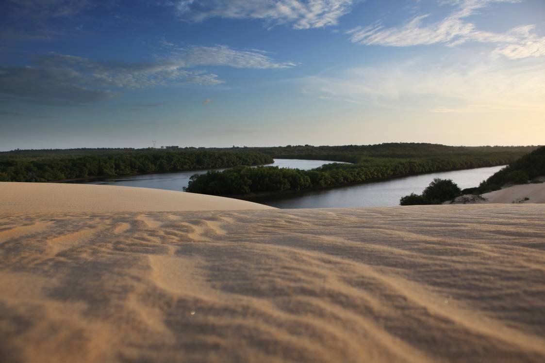 Uma vista de um rio do topo de uma duna de areia.