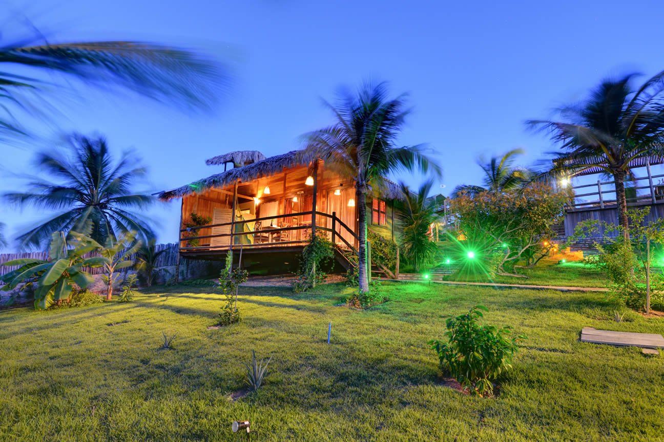 Uma casa de madeira cercada por palmeiras e um gramado verdejante.