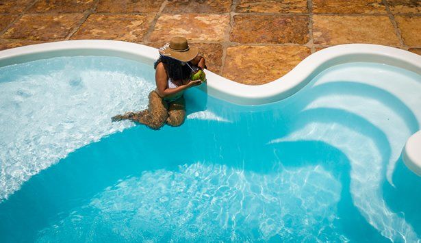 Uma mulher está sentada na borda de uma piscina.