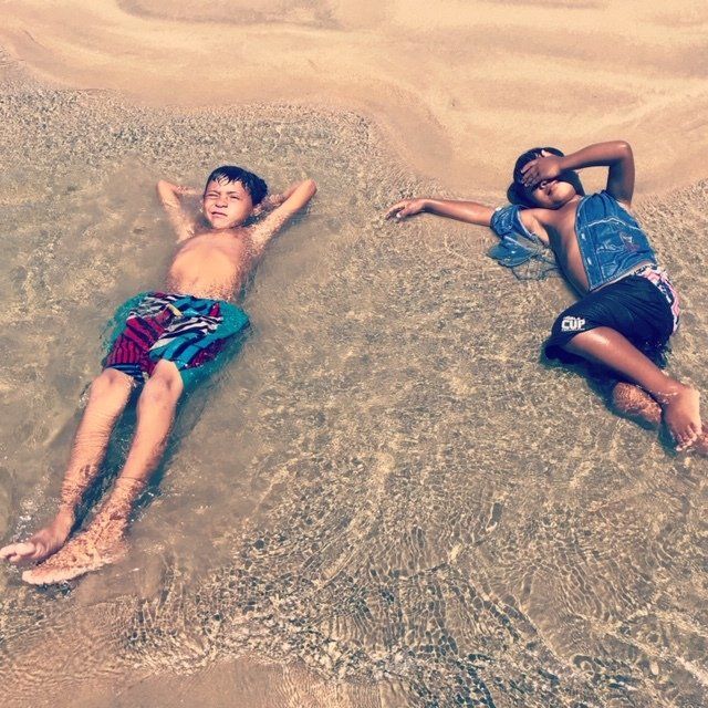 Dois meninos estão deitados na água na praia