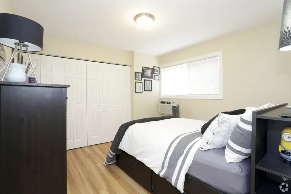 A bedroom with a bed , dresser , nightstand and lamp.