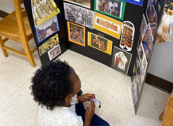 a Montessori child is sitting in front of a wall with pictures on it
