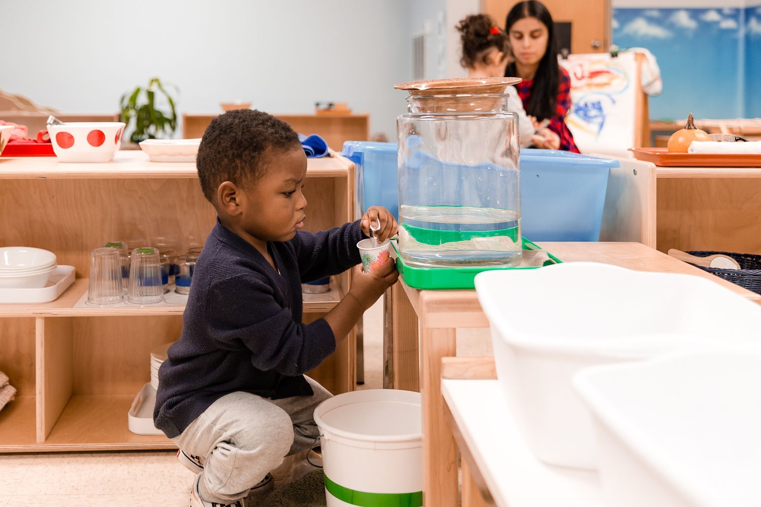 Montessori child pouring water for himself
