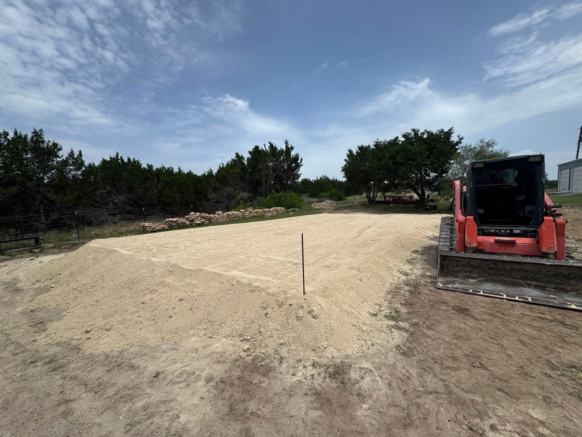 Construction site with a prepared gravel base, and a skid steer loader.