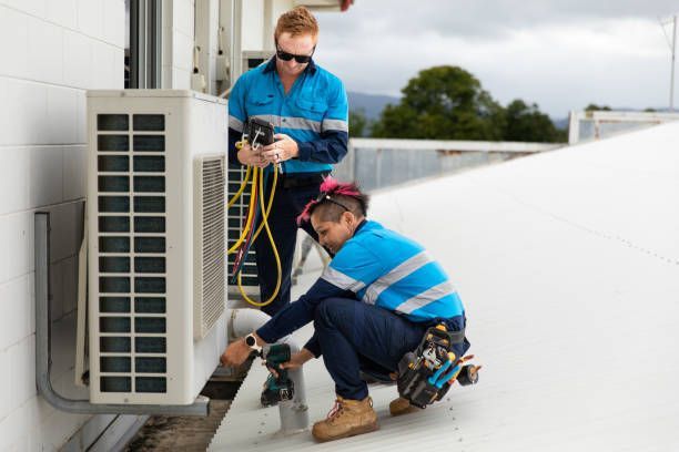 Two workers performing maintenance on an AC unit.