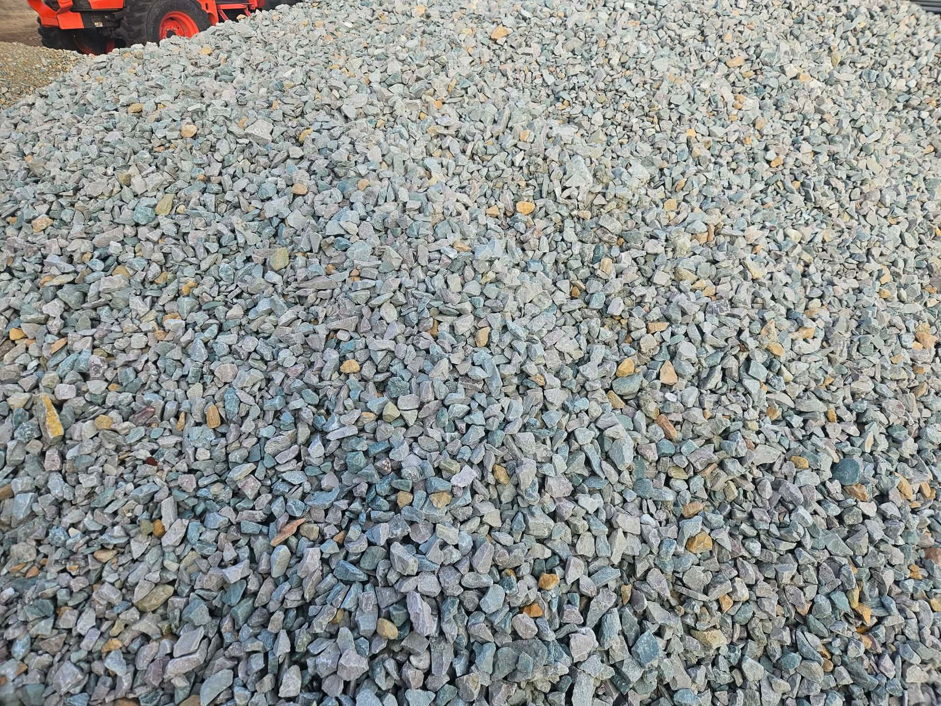 Red semi-truck driving on a dirt road, carrying steel beams and wood, kicking up dust under a cloudy sky.