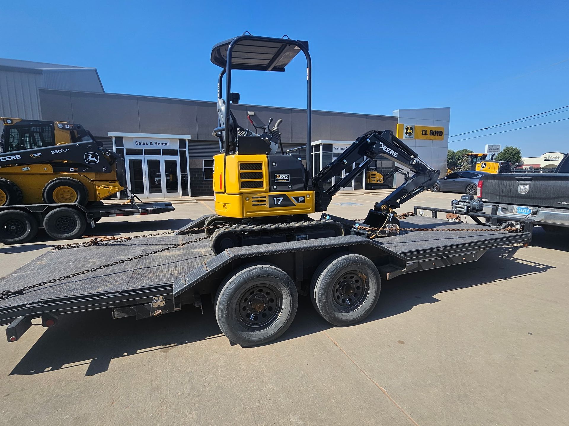 Black flatbed truck carrying construction materials on a road, blue sky.