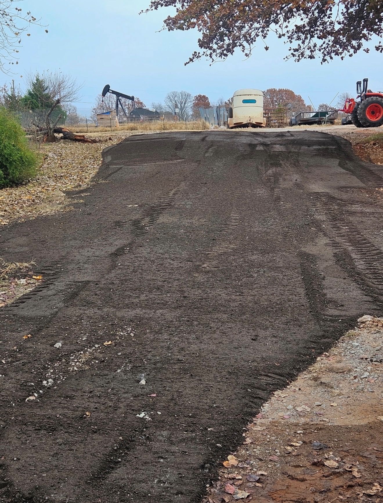 Orange dump truck hauling debris at a construction site; dusty atmosphere.