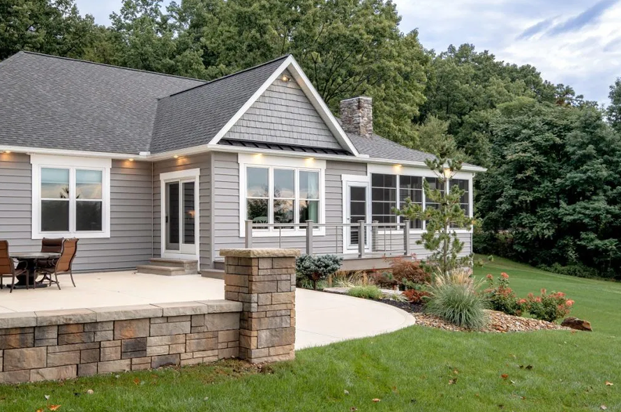 A house with a patio and a stone wall in front of it A house with a patio and a stone wall in front of it