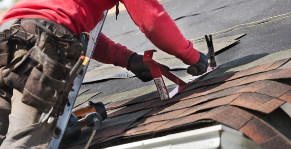 A man is working on the roof of a house.