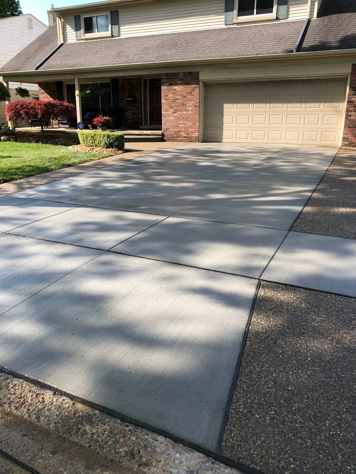 A concrete driveway in front of a house with a garage door.