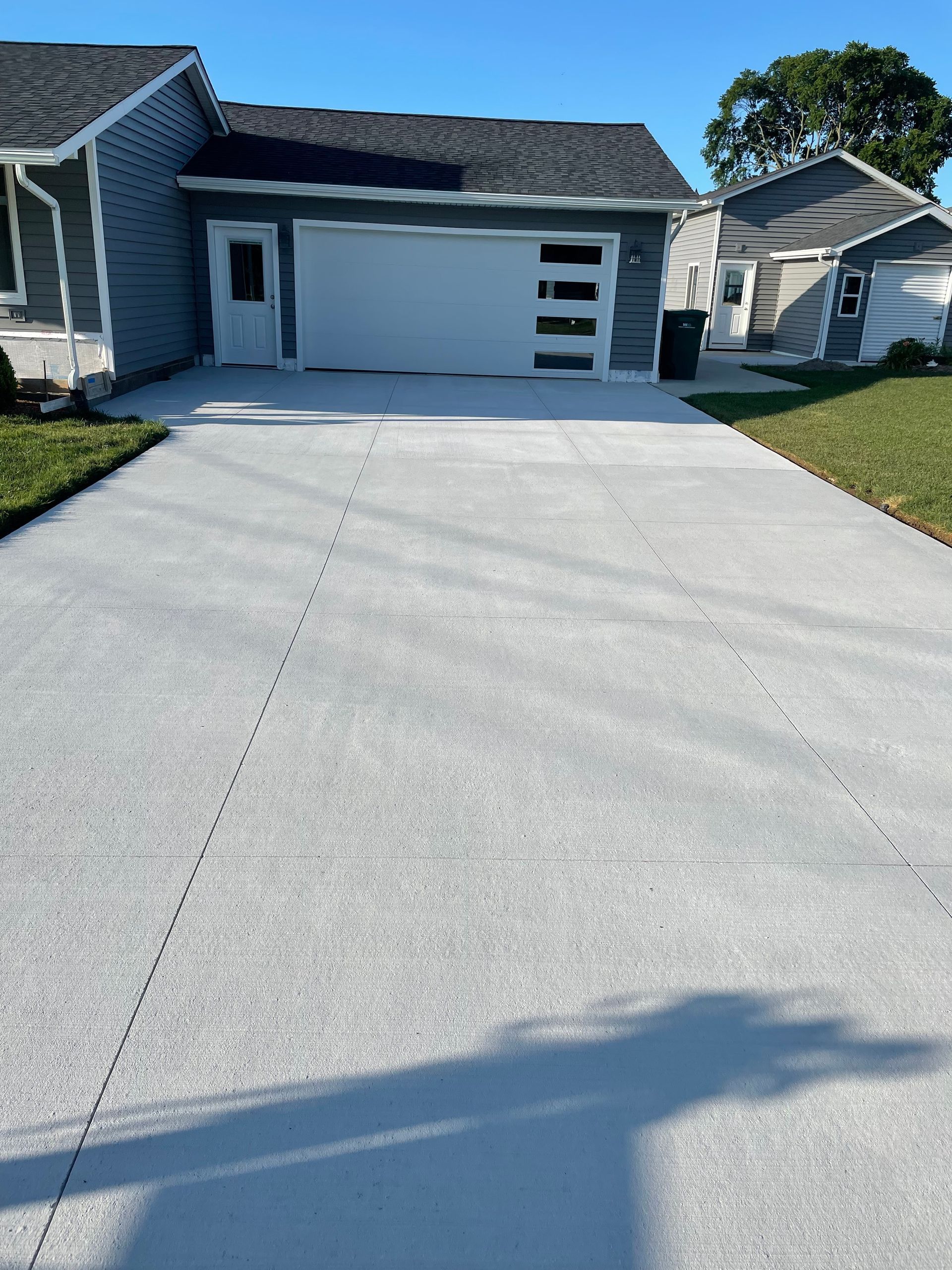 A concrete driveway leading to a house with a white garage door.