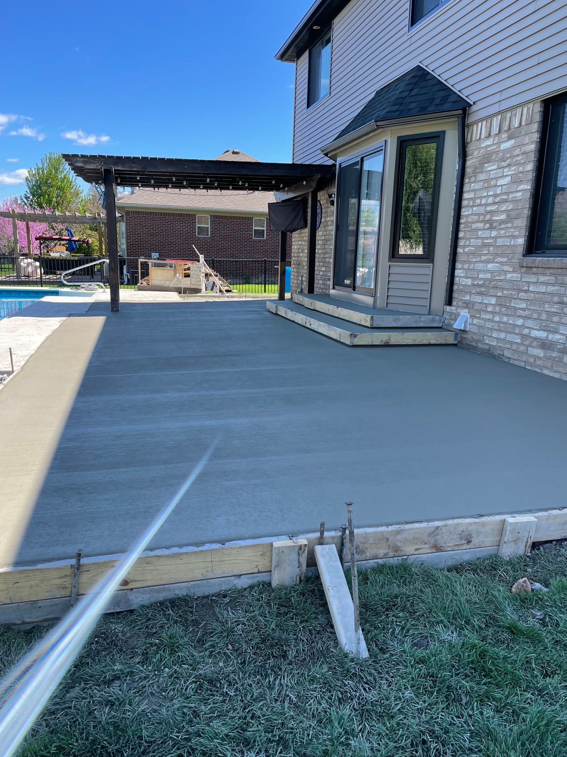 A concrete deck is being built in the backyard of a house.