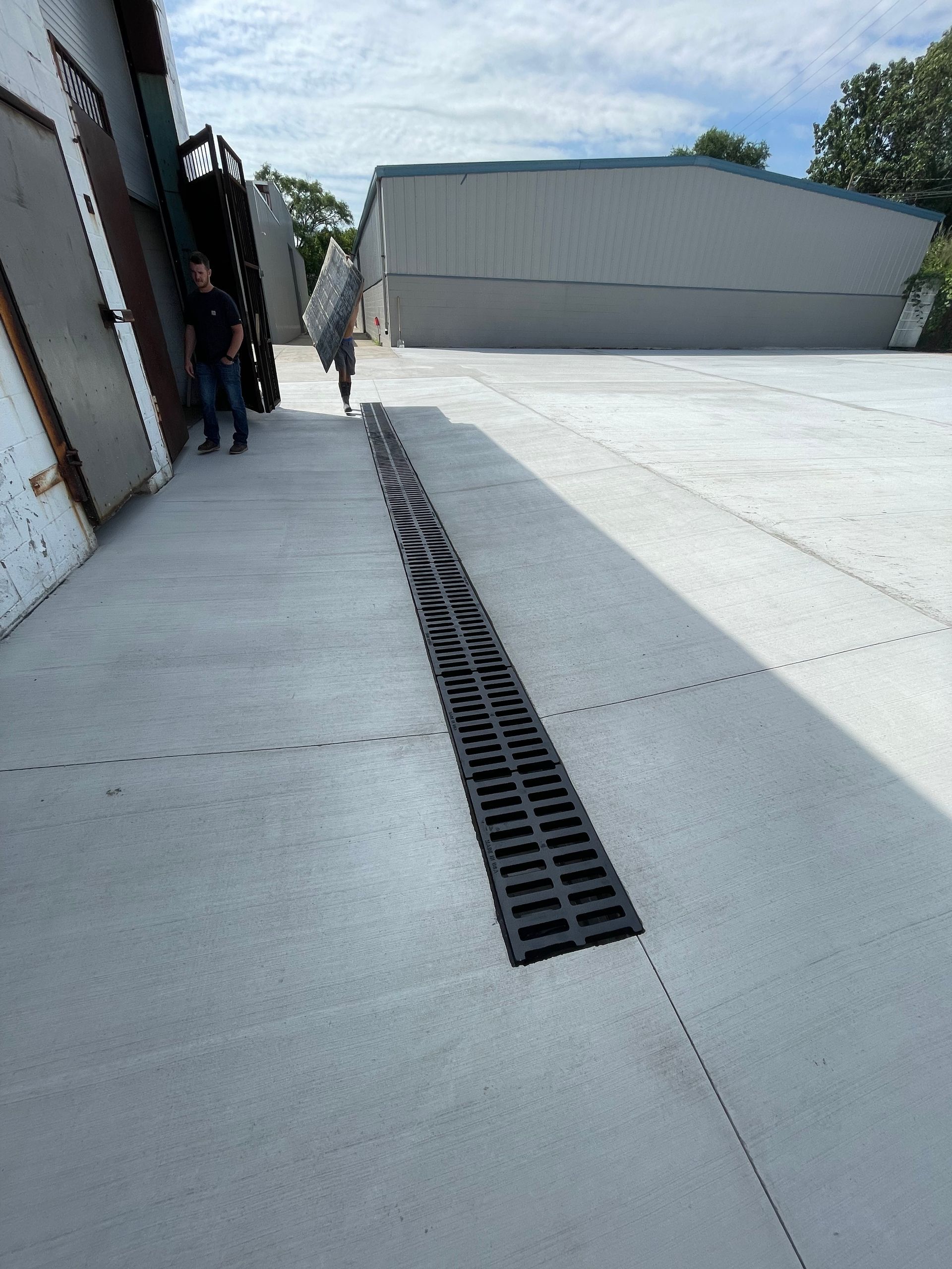 A manhole cover is on the sidewalk in front of a building.