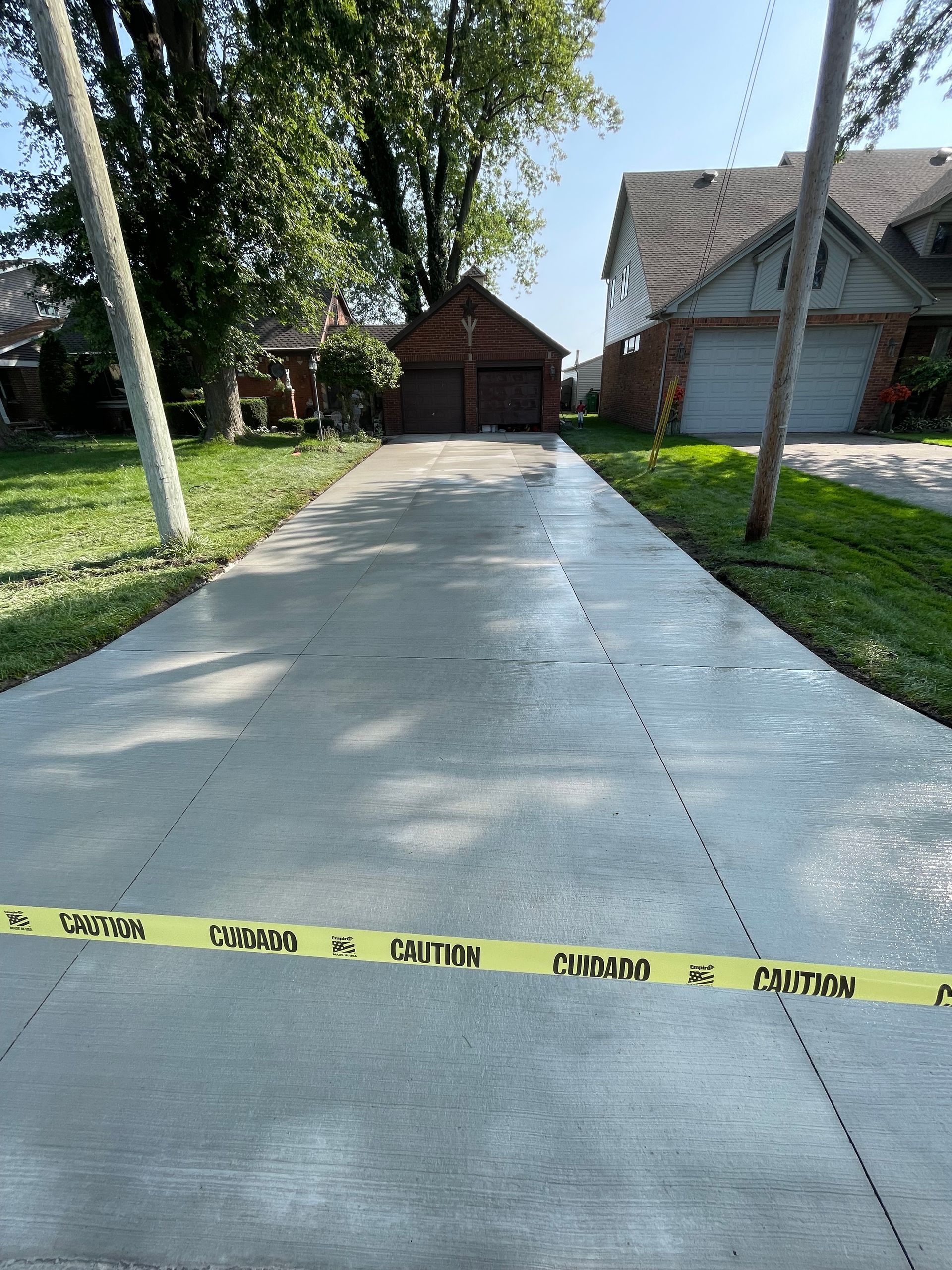 A concrete driveway with a yellow caution tape along the side of it.