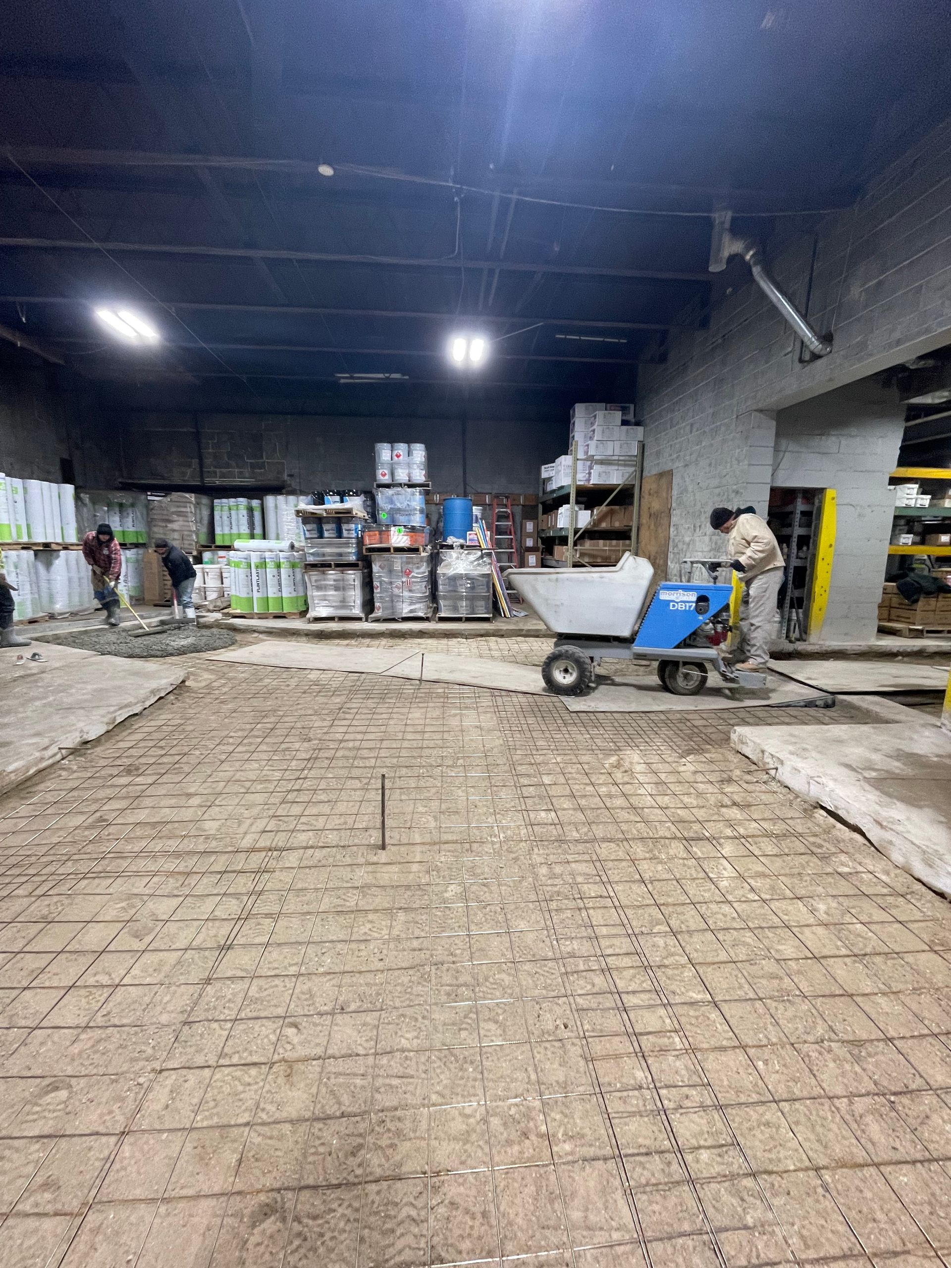 A man is pushing a wheelbarrow in a warehouse.