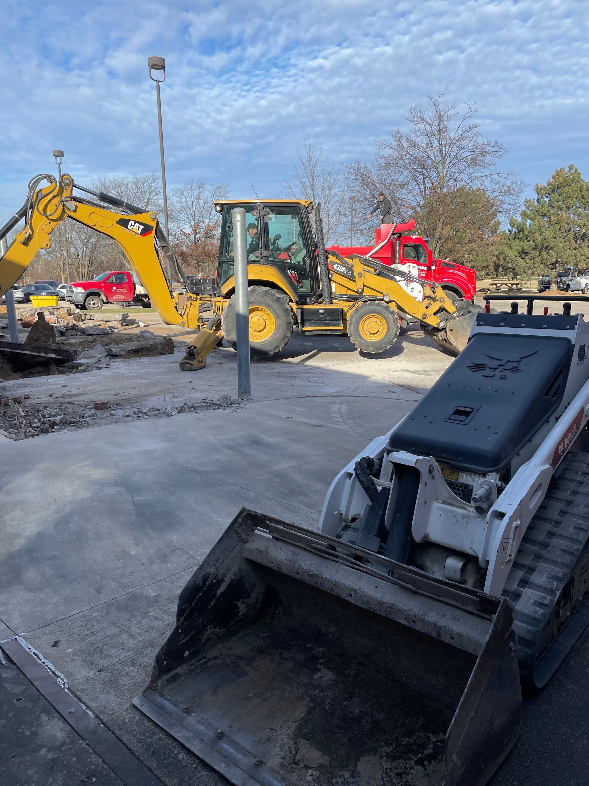 A bulldozer and an excavator are parked in a parking lot.