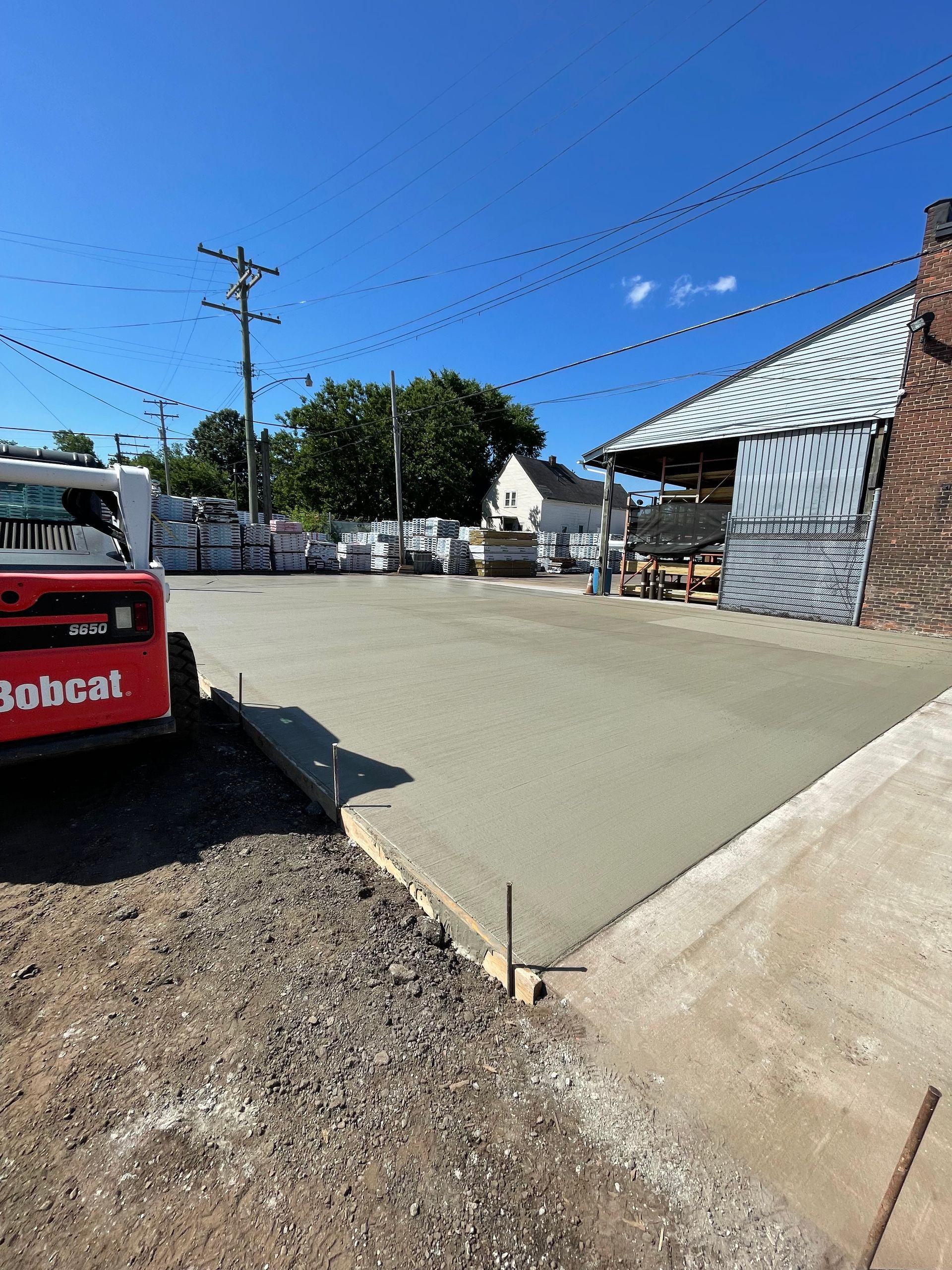 A bobcat is parked in a parking lot next to a building.