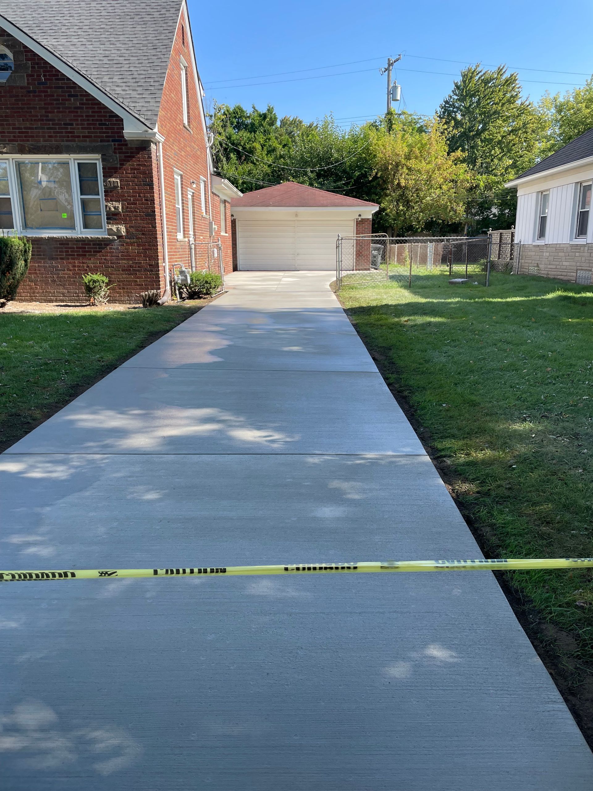 A concrete driveway leading to a brick house with a garage.