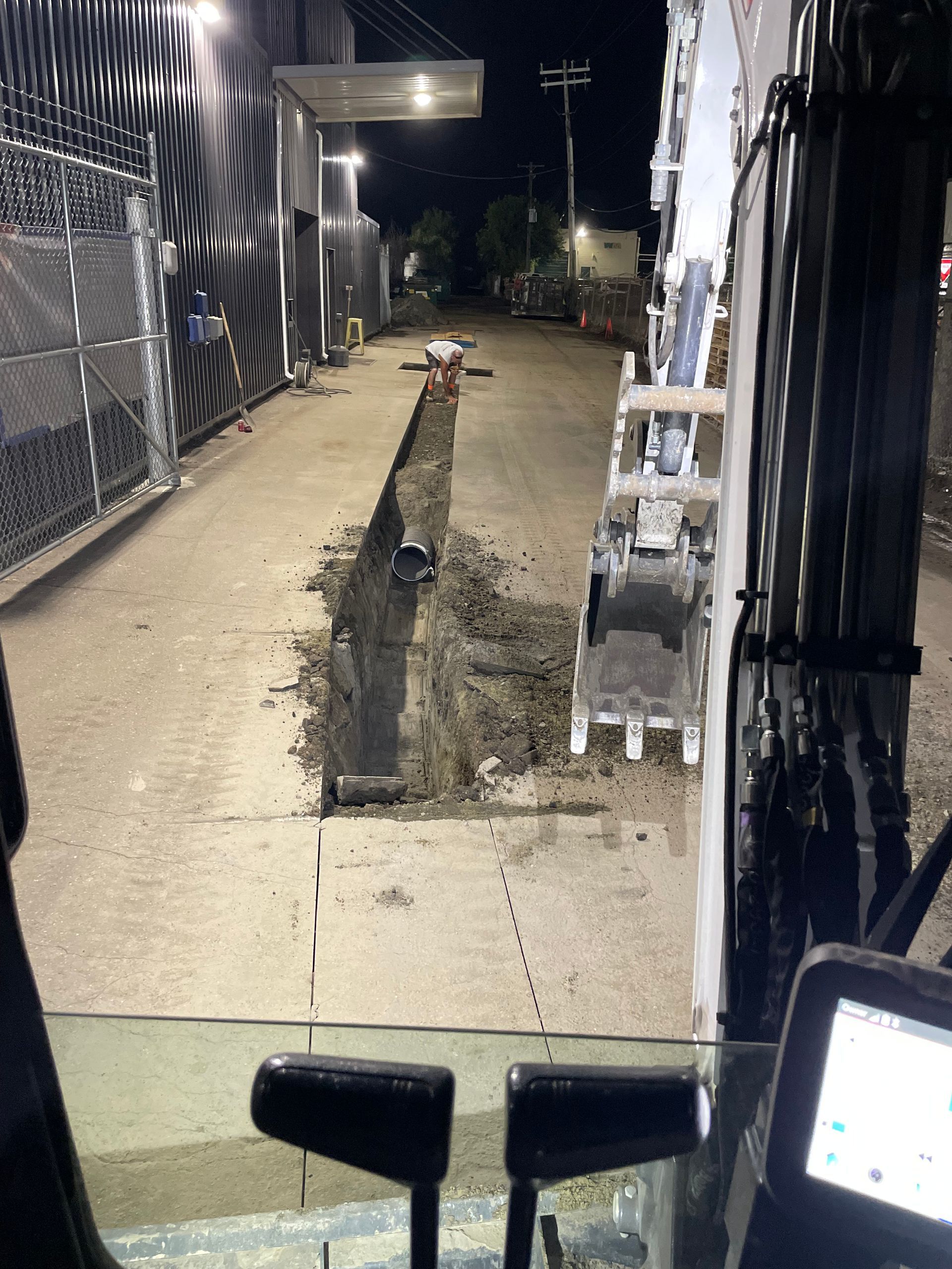 A forklift is driving down a dirt road at night.