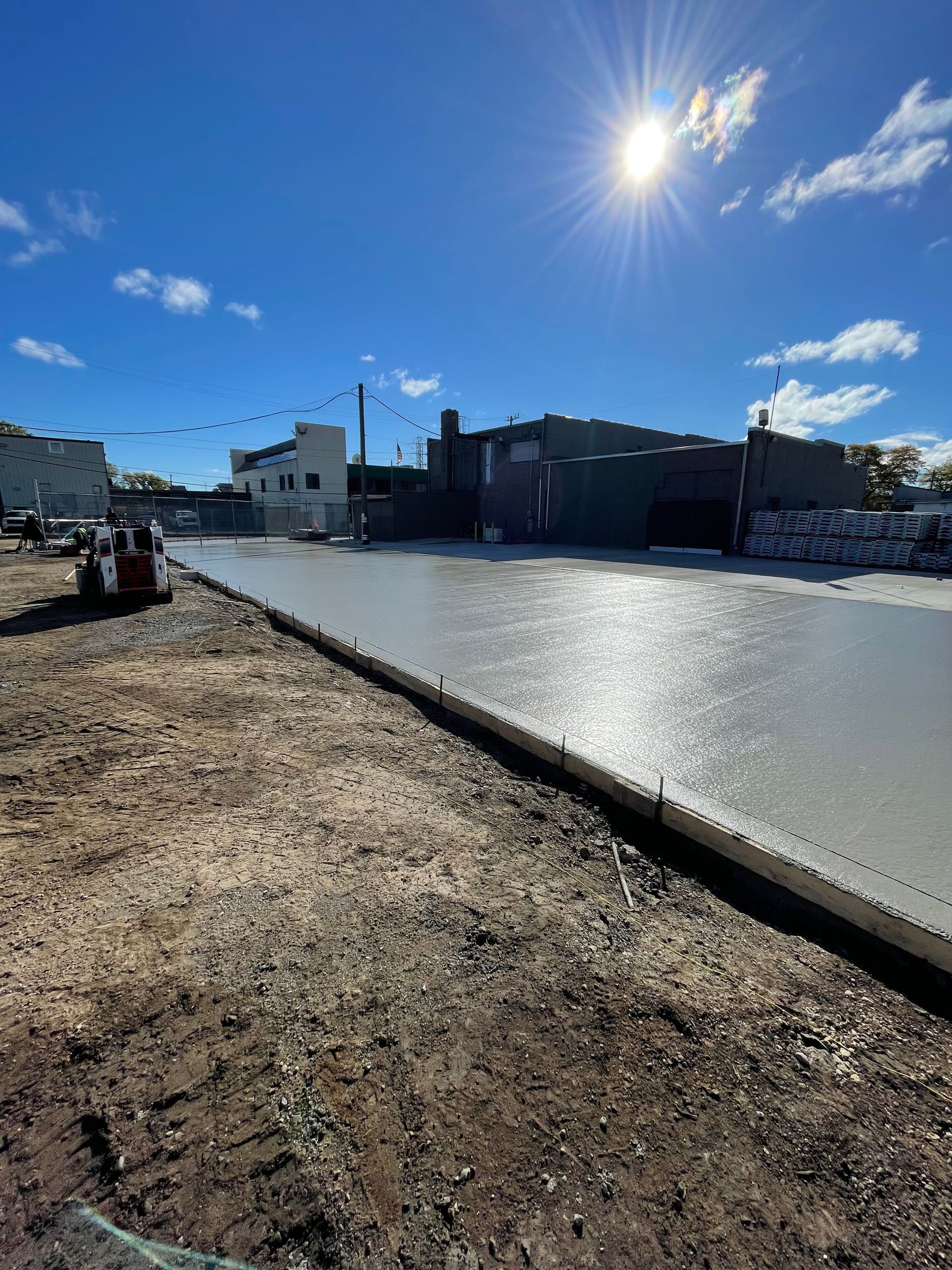 A concrete road is being built on a sunny day.