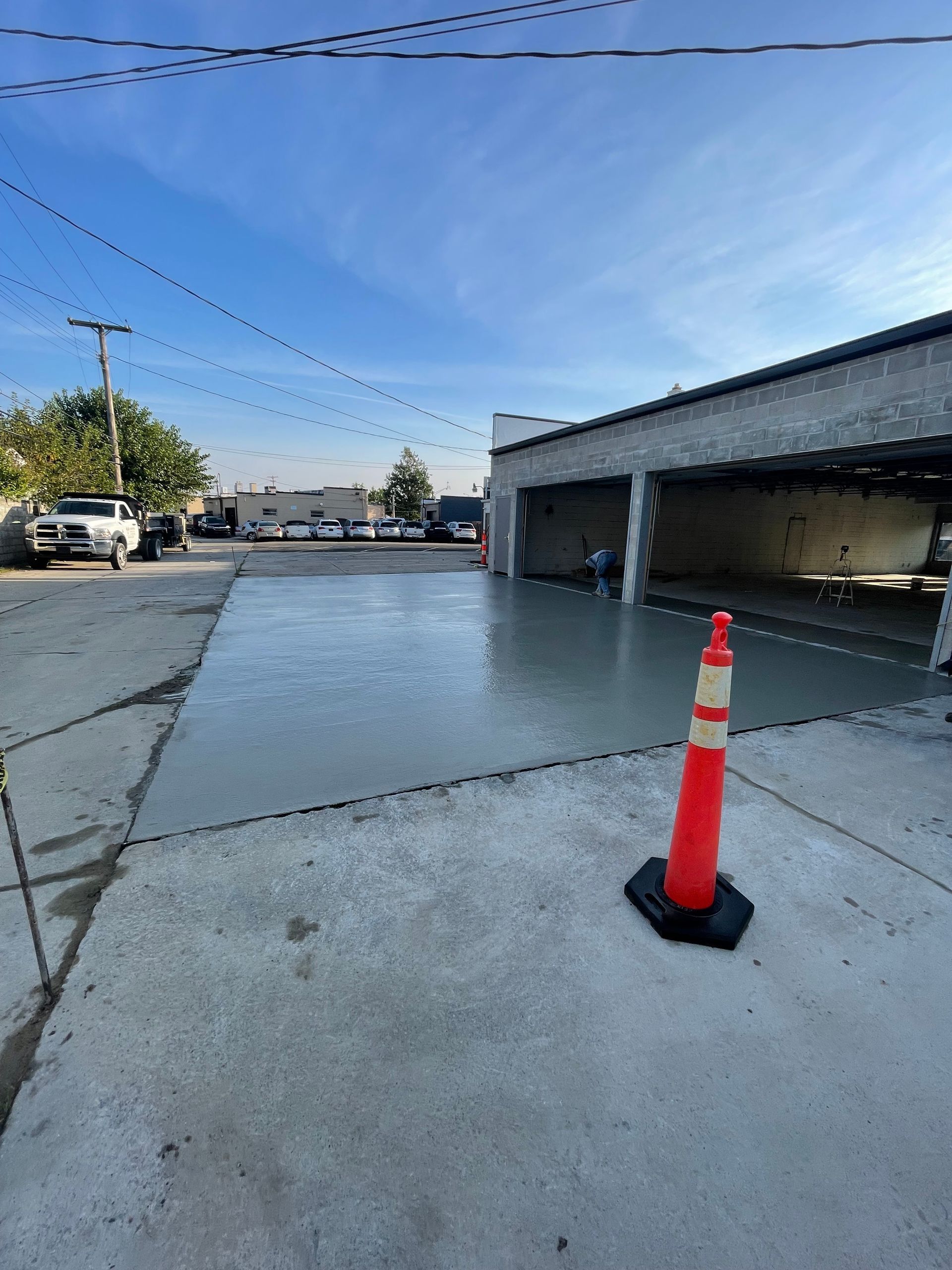 A red and white traffic cone is sitting on the sidewalk in a parking lot.