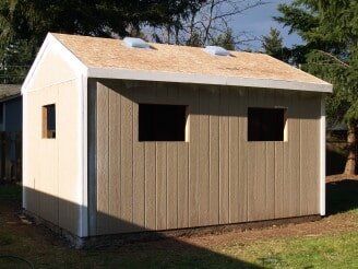 Tan and white shed with two windows, two vents on roof, and a wood grain exterior.
