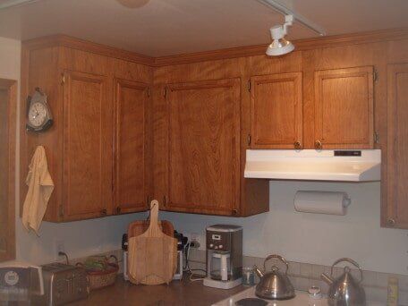 Wooden kitchen cabinets with a range hood, toaster, and coffee maker on the counter.