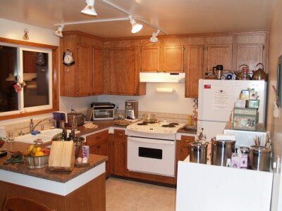 Kitchen with wooden cabinets, white appliances, and a small island.
