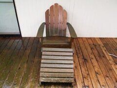 Wooden Adirondack chair on a wooden deck.