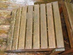 Wooden bench seat made of vertical planks, weathered and worn.