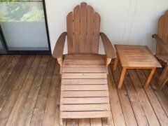 Wooden Adirondack chair and side table on a wooden deck.