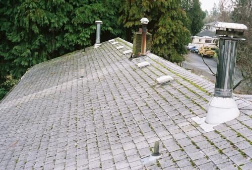 Gray, weathered roof with several chimneys and vents.