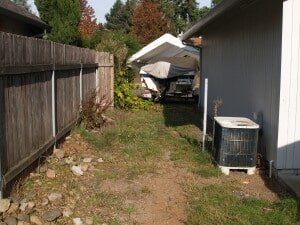 Grassy side yard with a wooden fence on the left.
