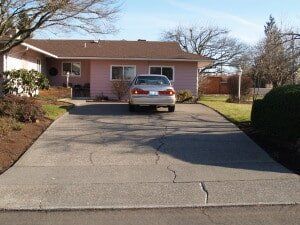 Tan car parked in driveway of a pink house on a sunny day.