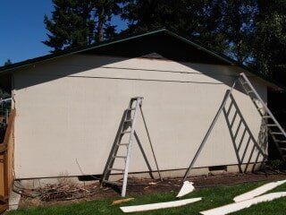Exterior view of a beige building with ladders leaning against it.