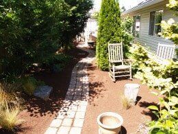 Stone path through a garden, leading to a house. 
