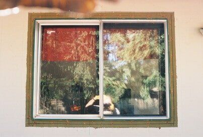Sliding window with a red-toned shade on the left side, reflecting a colorful outdoor scene.