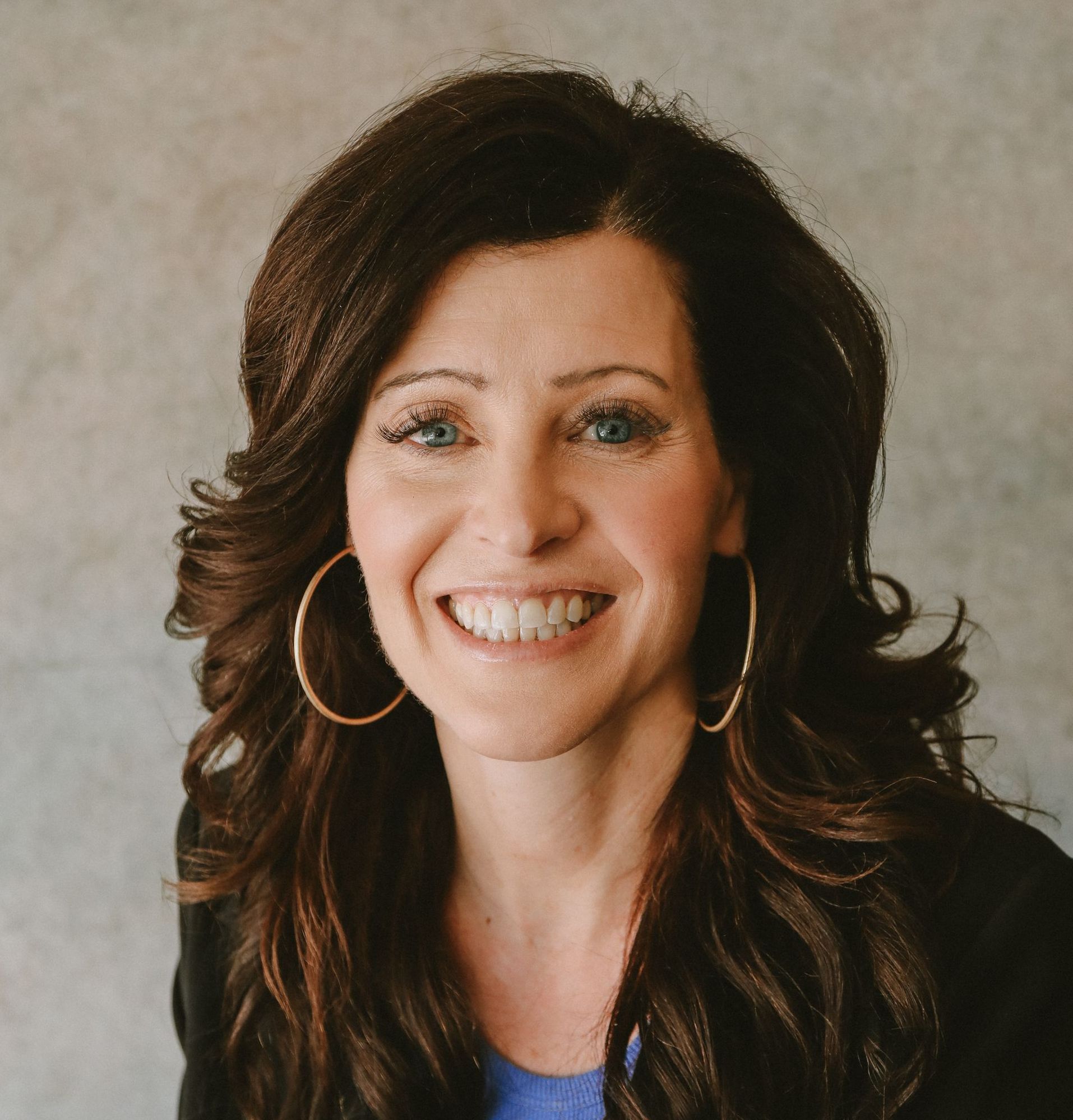 Agent Jauqueline Gartner with long hair and hoop earrings is smiling for the camera.