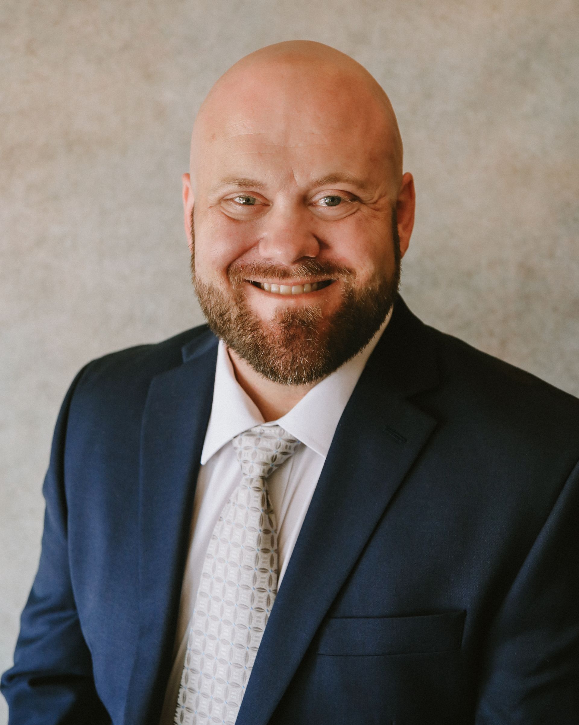 Third-generation agent Shane Ferguson smiles in a navy blue suit and tie.