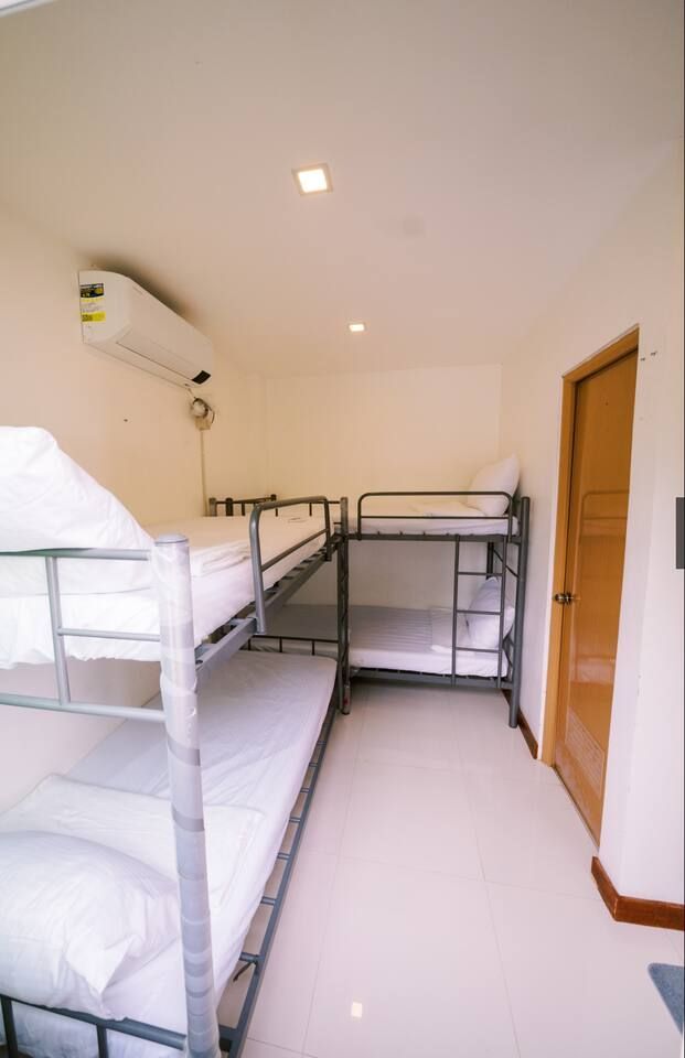 Bunk beds in a white-walled room with a door and an air conditioner.