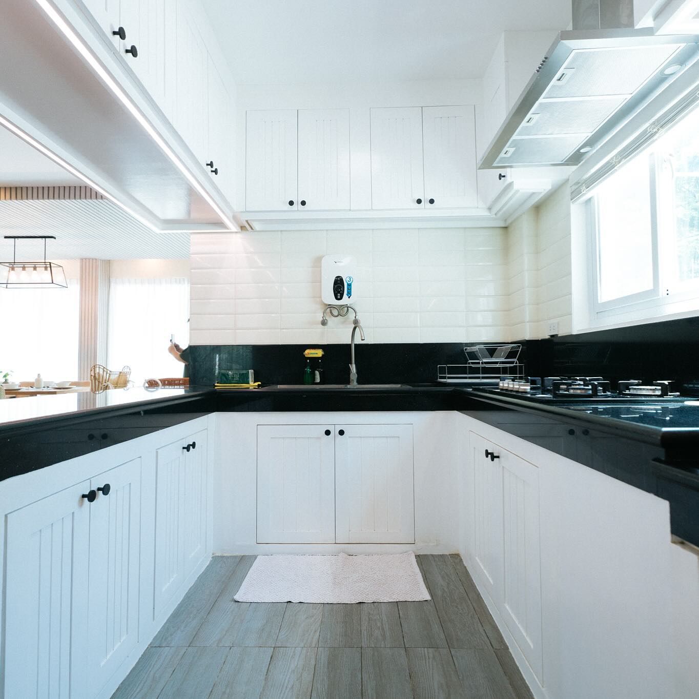 White kitchen with black countertops and cabinets. Includes a stove, sink, and overhead lighting.